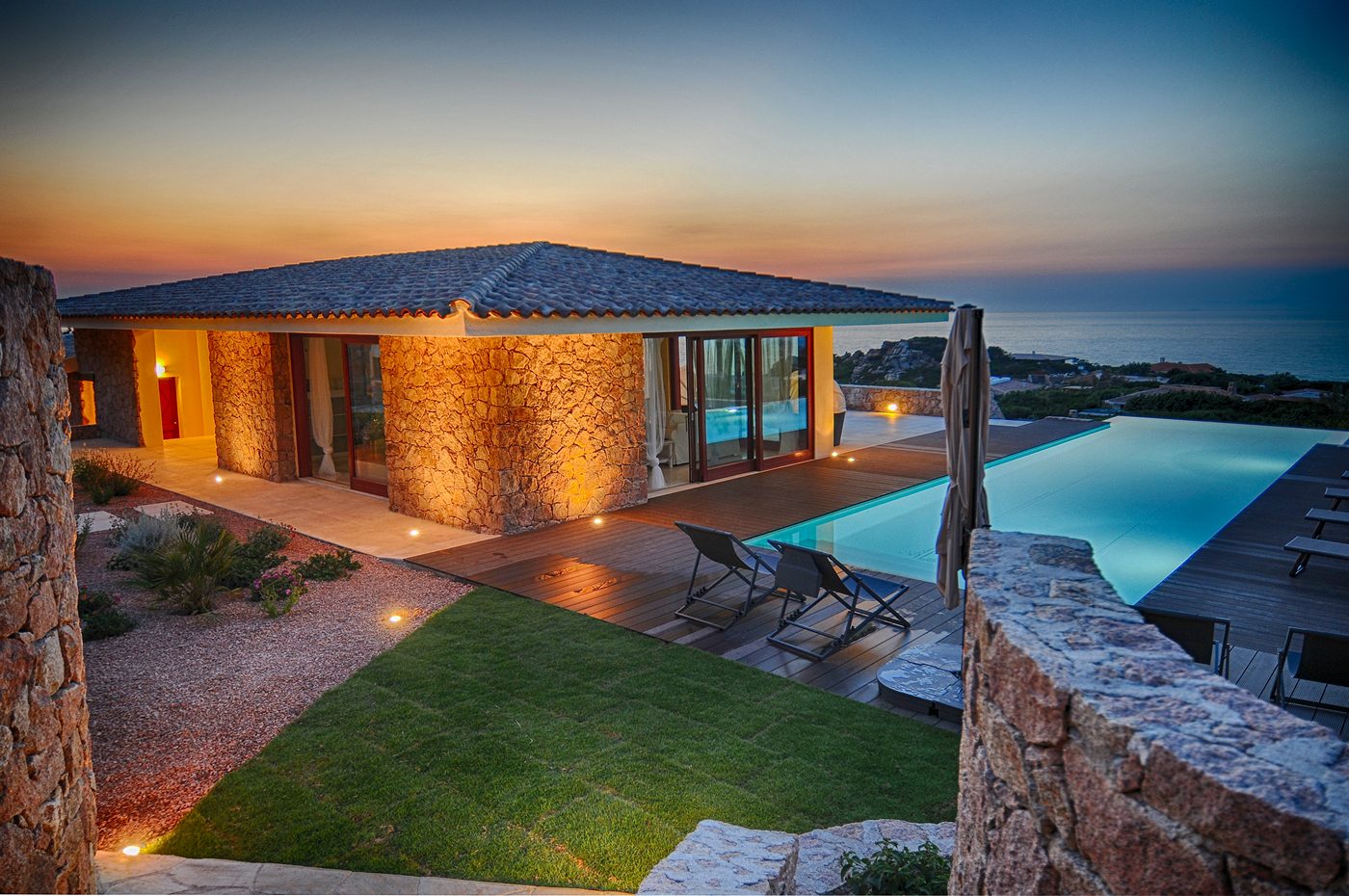 Villa with illuminated pool at dusk, overlooking the Mediterranean